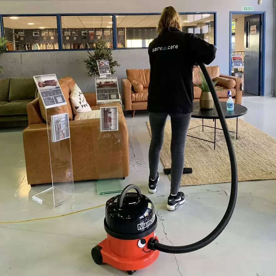 Person hoovering office with Numatic vacuum cleaner.