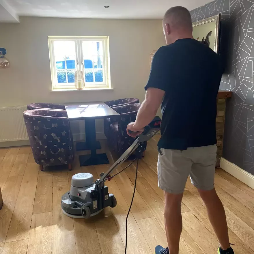 Person using machine to polish wooden floor indoors.
